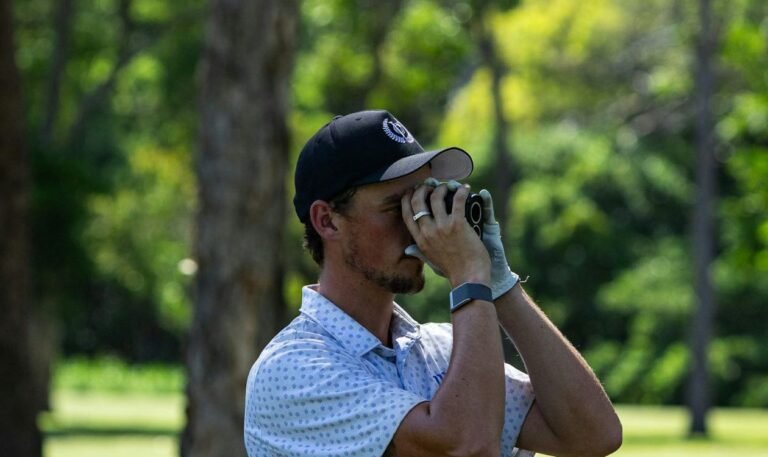 Golfer looking through a golf rangefinder to check the distance to the green